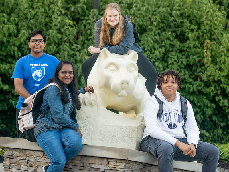 Students sitting on the Nittany Lion Statue.