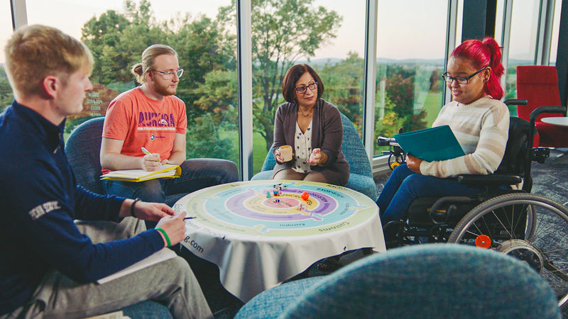 Three students having a discussion with President Neeli Bendapudi in Polli Hall, the Graham Center for Innovation and Collaboration.