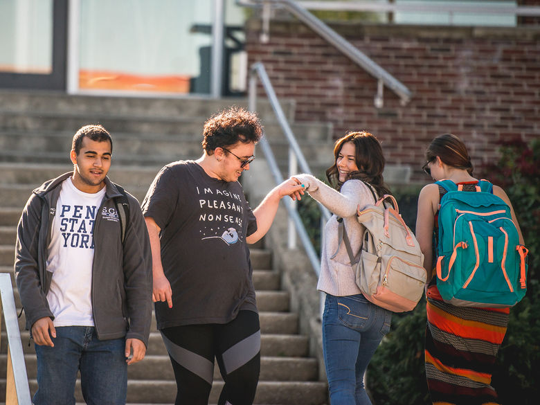 Students passing each other on the steps outside the lower level of the John J. Romano Administration building.