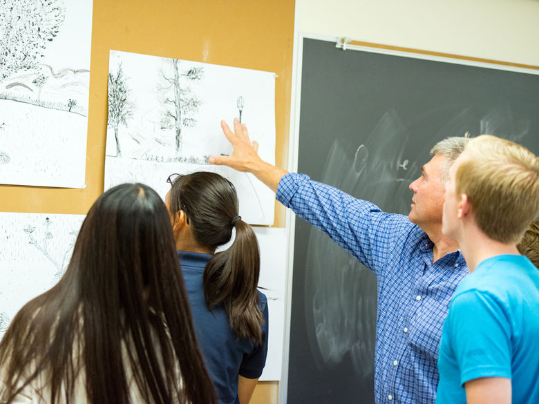 Professor and students reviewing art during a class.