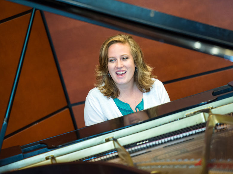 Student playing the piano and singing in the Community Room.