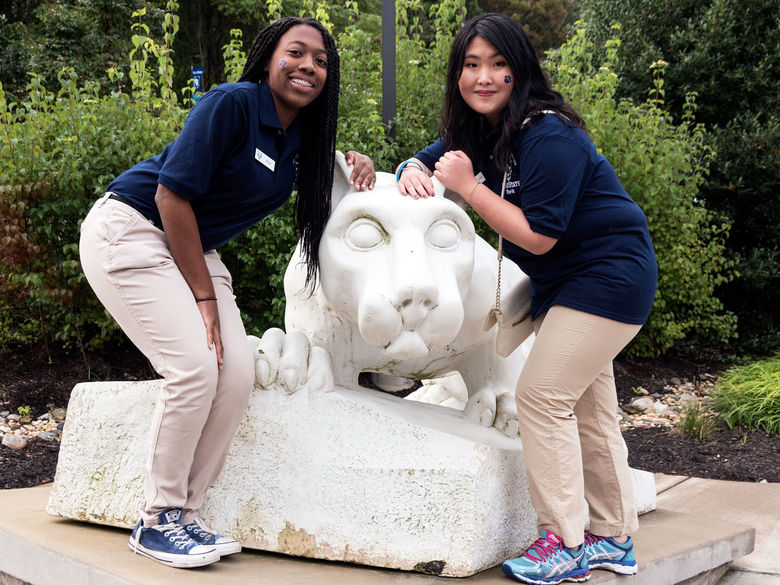 Two Lion Ambassadors pose with the Nittany Lion statue
