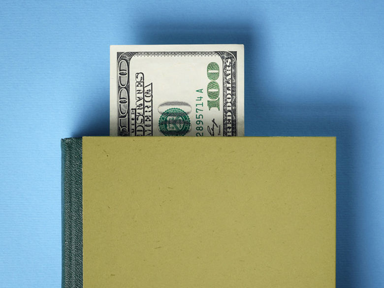 a hundred dollar bill sticking out of a book Financial Literacy