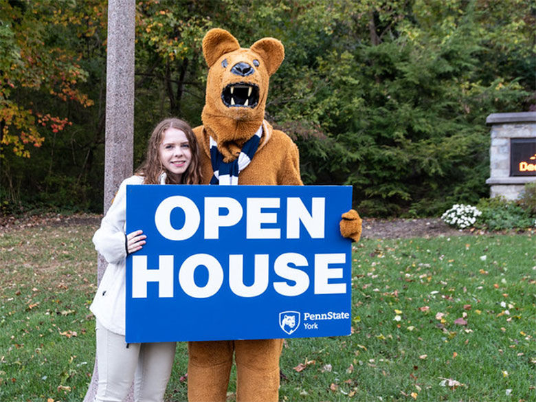 Student and Nittany Lion mascot holding an Open house sign