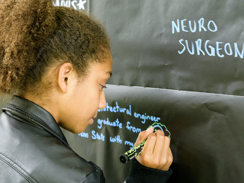 A student writing on the chalk wall during Pathways 2016.