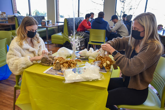 Two young women at a table stuffing plushed animals