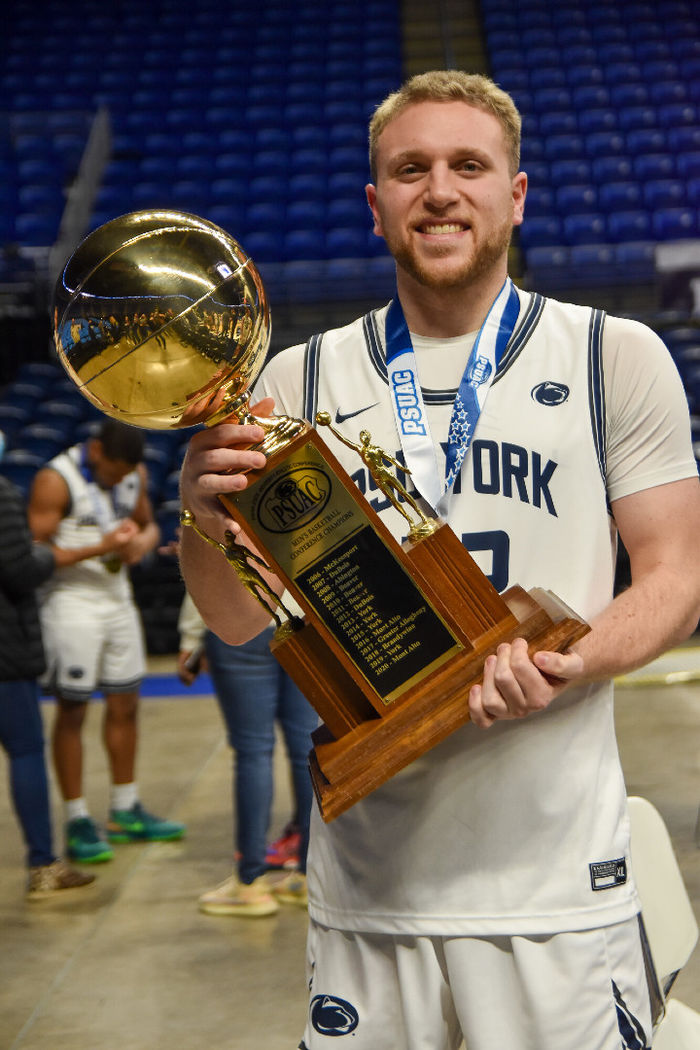 Basketball player holding PSUAC CHampionship trophy