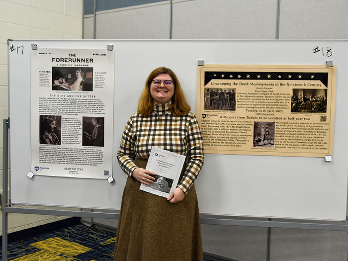 Female student wearing glasses stands in front of her award-winning research poster.