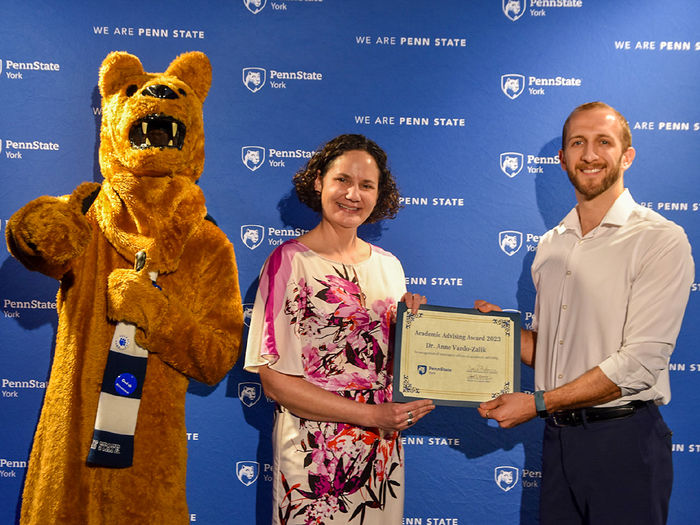 Nittany Lion character along with female and male faculty member doing an awards presentation