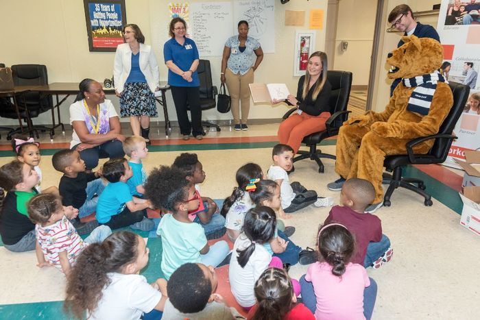 A student reads to children.