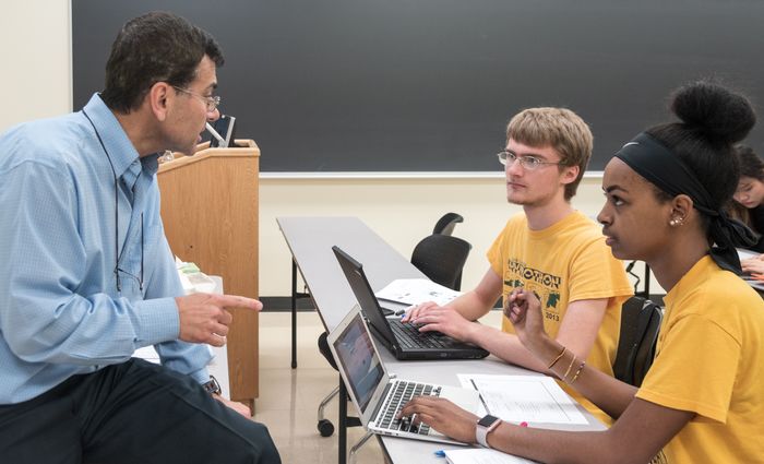 Professor Ali Kara works with a small group of students during a business class.