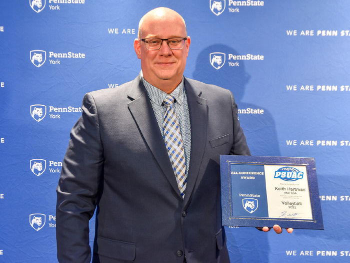 Adult male wearing glasses holding an award certificate.