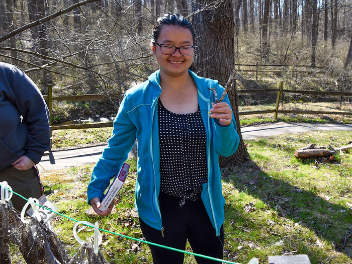 Female Asian student with dark hair and glasses collects specimens in Nixon Park