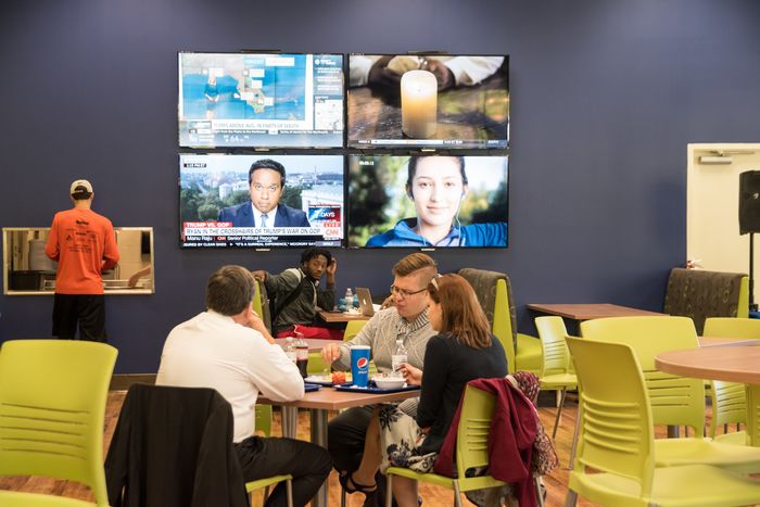 Students sitting in front of a wall of televisions in Rosie’s.