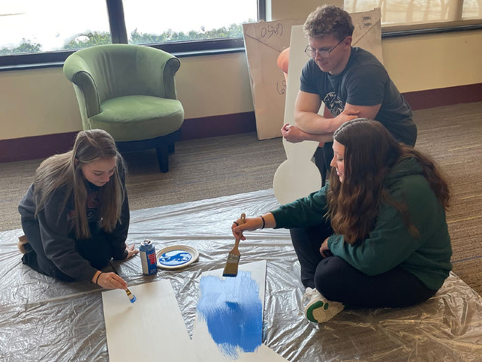 Two females and a male paint a giant letter K