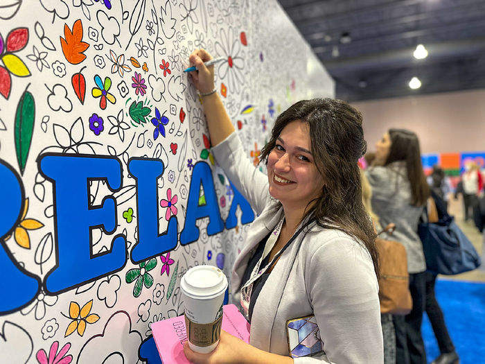 Feamle with long brown hairs colors shapes on a wall during a women's conference in Philadelphia.