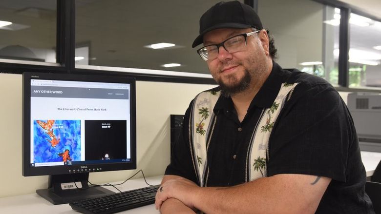 Adult student wearing glasses and a hot at a computer displays the campus online magazine.