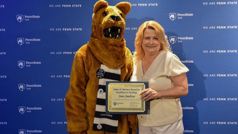 Nittany Lion costumed character presents awatd to female with long blonde hair