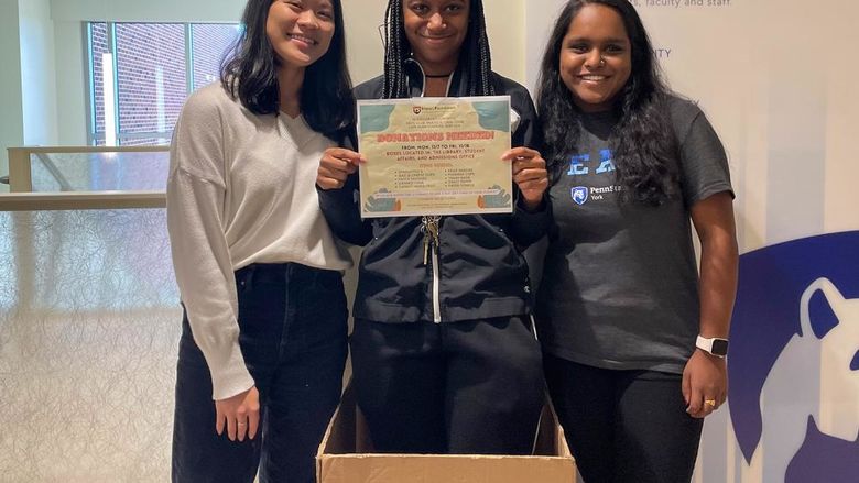 Three ethnic female ethnic Penn State York students promote an upcomig donation drive 