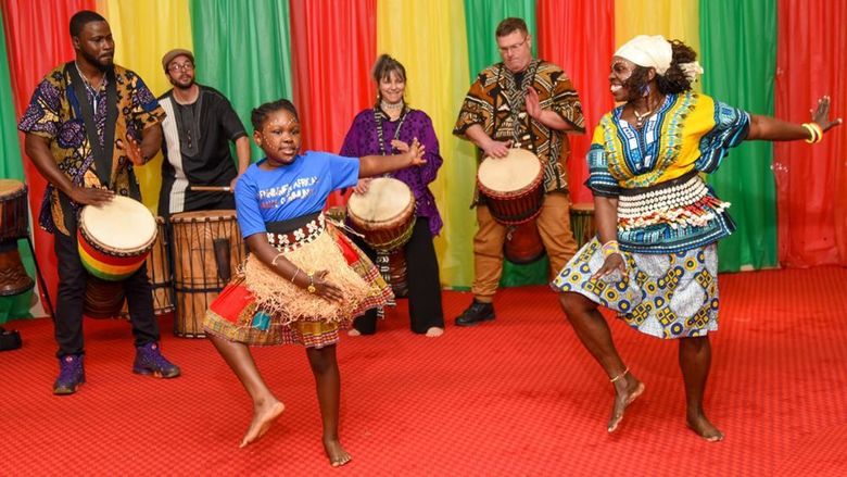 Group of African American and white performing dancing and playing instruments.