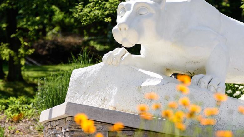 Nittany Lion Statue with spring flowers blooming.