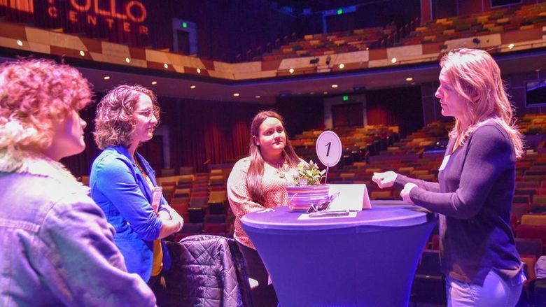 Three students interacting with business professional