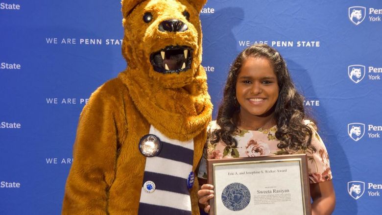 Penn State Nittany Lion and female student pose with award