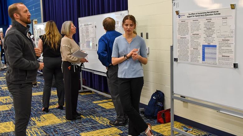 Research posters displayed on boards with students and faculty reviewing them