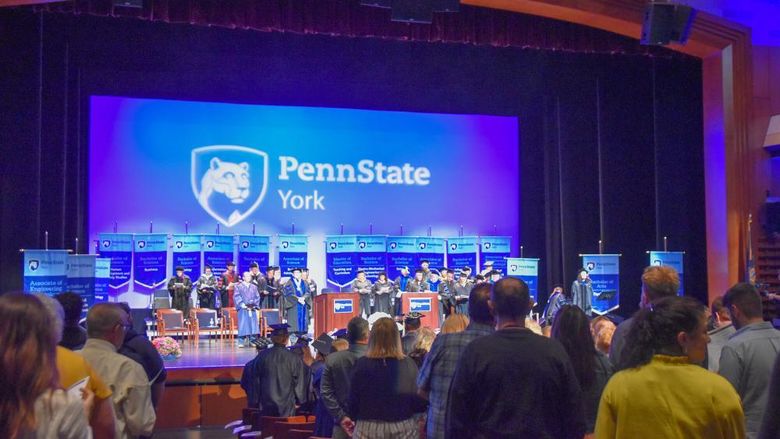 Theatre filled with people watch a commencement ceremony on stage