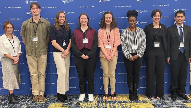 Eight student research award-winners  standing in fromt of a banner