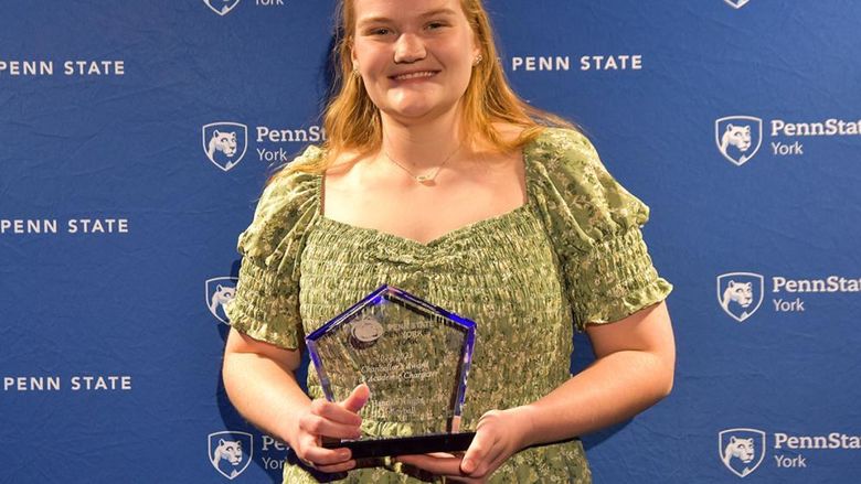 Female student with long blonde hair holding an athletic award.