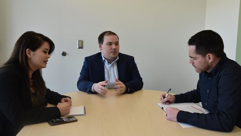 Three people have a discussion around a table