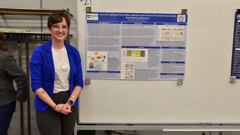 Female caucasian student standing in front of science display poster