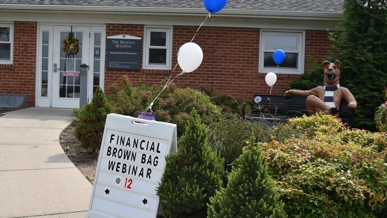 Picture of building with Nittany Lion statue sitting on a bench, and a sign for a webinar series