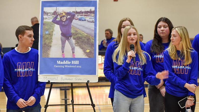 Male and female students on either side of an easel displaying a photo of the late Maddie Hill