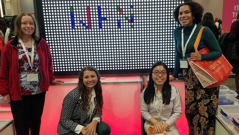 Four young women in front of a light board