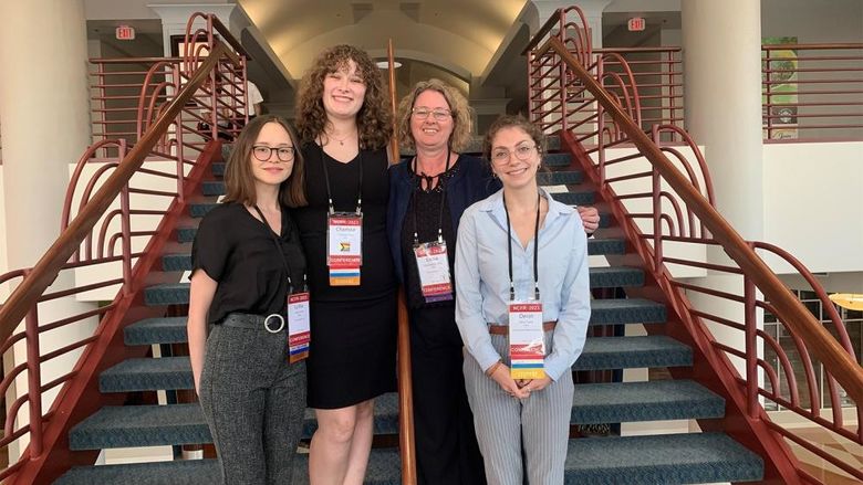 Three students and a faculty member standing on a stairway