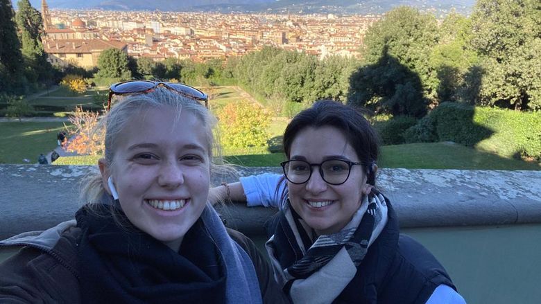 Two women standing in front of a scenic background.