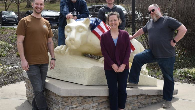 Four men and a woman standing around the lion shrine statue.