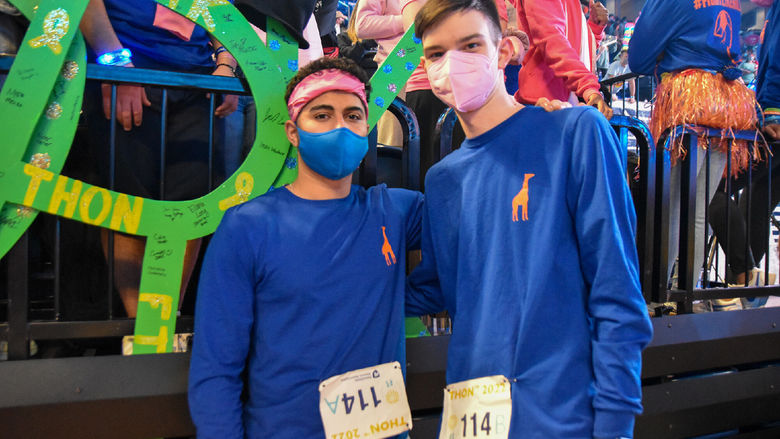 Two young men wearing long-sleeved blue shirts participate in dance marathon.