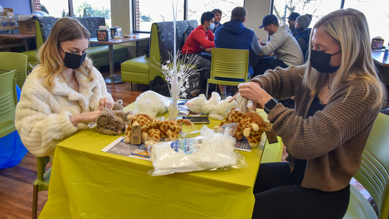 Two young women at a table stuffing plushed animals