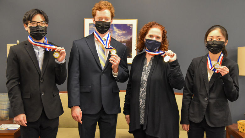 Thee young men and one women, professionally dress,  hold first-place medallions