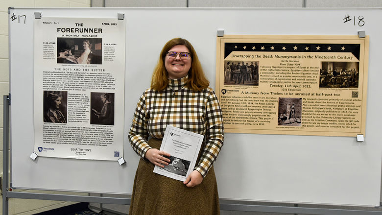 Female student wearing glasses stands in front of her award-winning research poster.