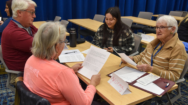 Three older adults, one male and two females, work with female student.