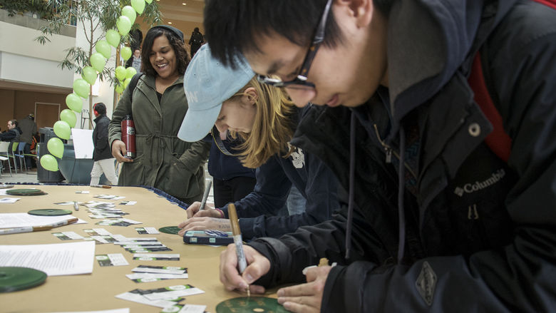 Students writing down messages on green CDs