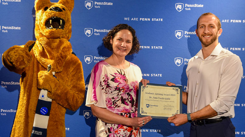 Nittany Lion character along with female and male faculty member doing an awards presentation
