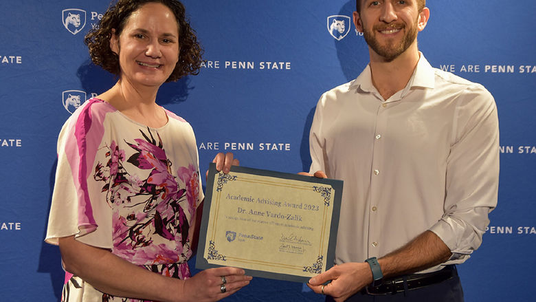 Female with brown hair and male with beard holding a certificate