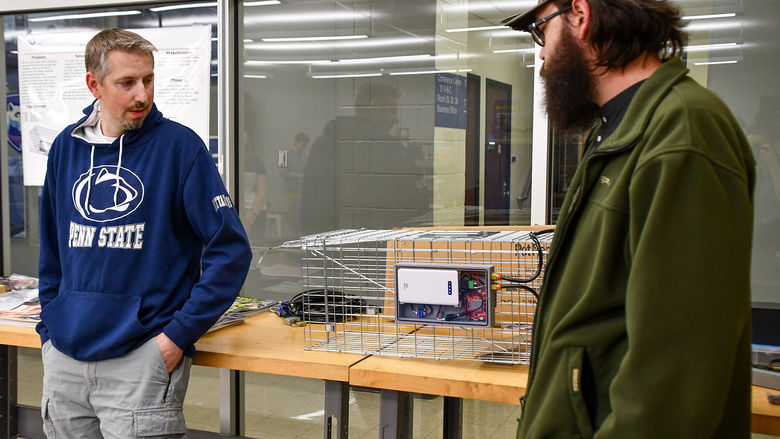 Two engineering students presenting their automated trap system.