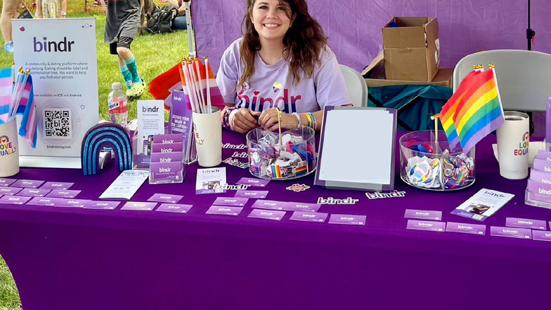 Female with long dark hair displaying items at a vendor table