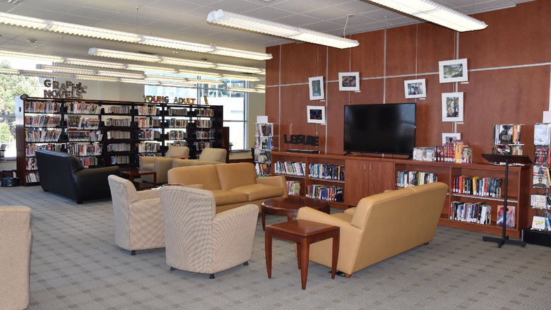 Couches, big screen TV, book stacks, and other chairs in the library.